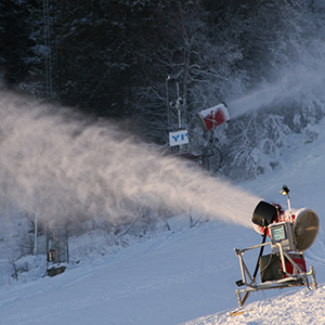 En snökanon sprutar snö i skidbacke