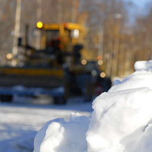 En snöhög i förgrunden med en traktor i bakgrunden